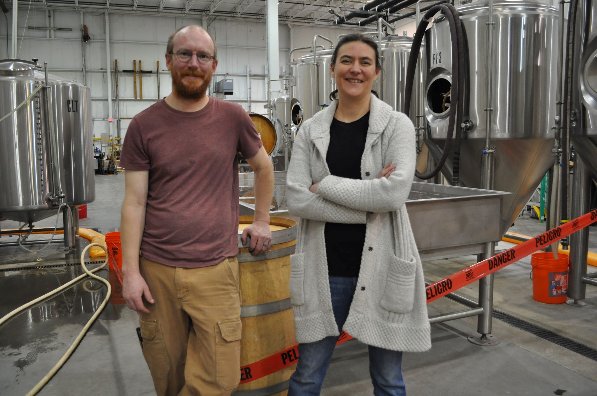 Joe Jasper and Lindsay Naylor Jasper stand in the brewing cellar with their stainless steel equipment